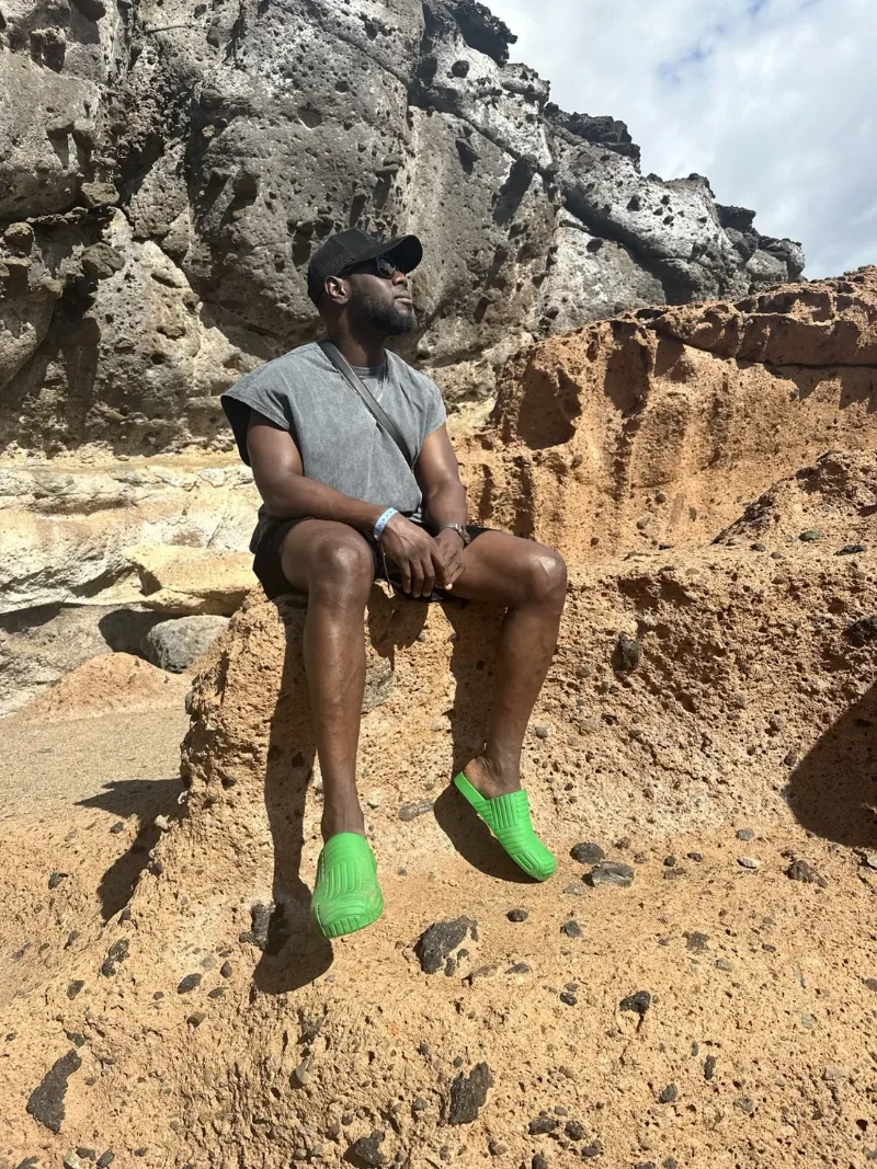 Denis sitting among sunlit volcanic rocks in Tenerife